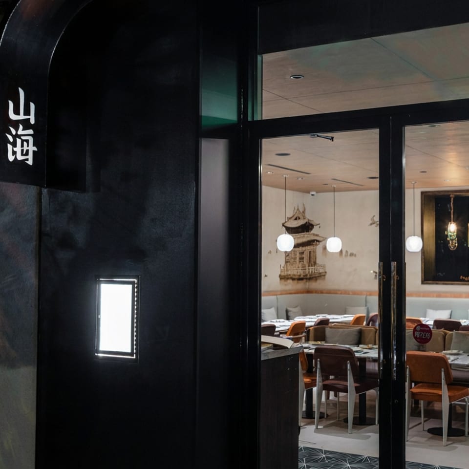 Elegant Japanese restaurant entrance with black doors, illuminated Chinese characters, warm dining room, pendant lights, and numbered address 2508.